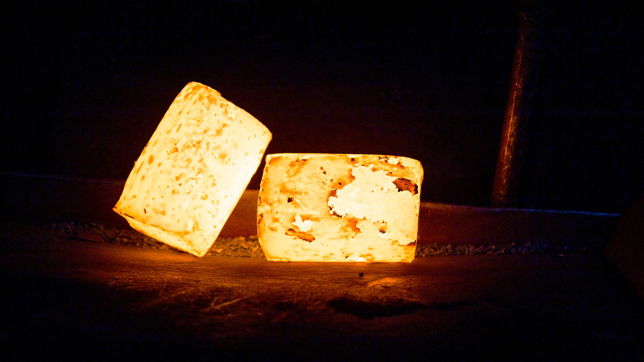 a pair of heavy hot glowing cylindrical workpieces ready to forging on dark metal background, close-up with selective focus